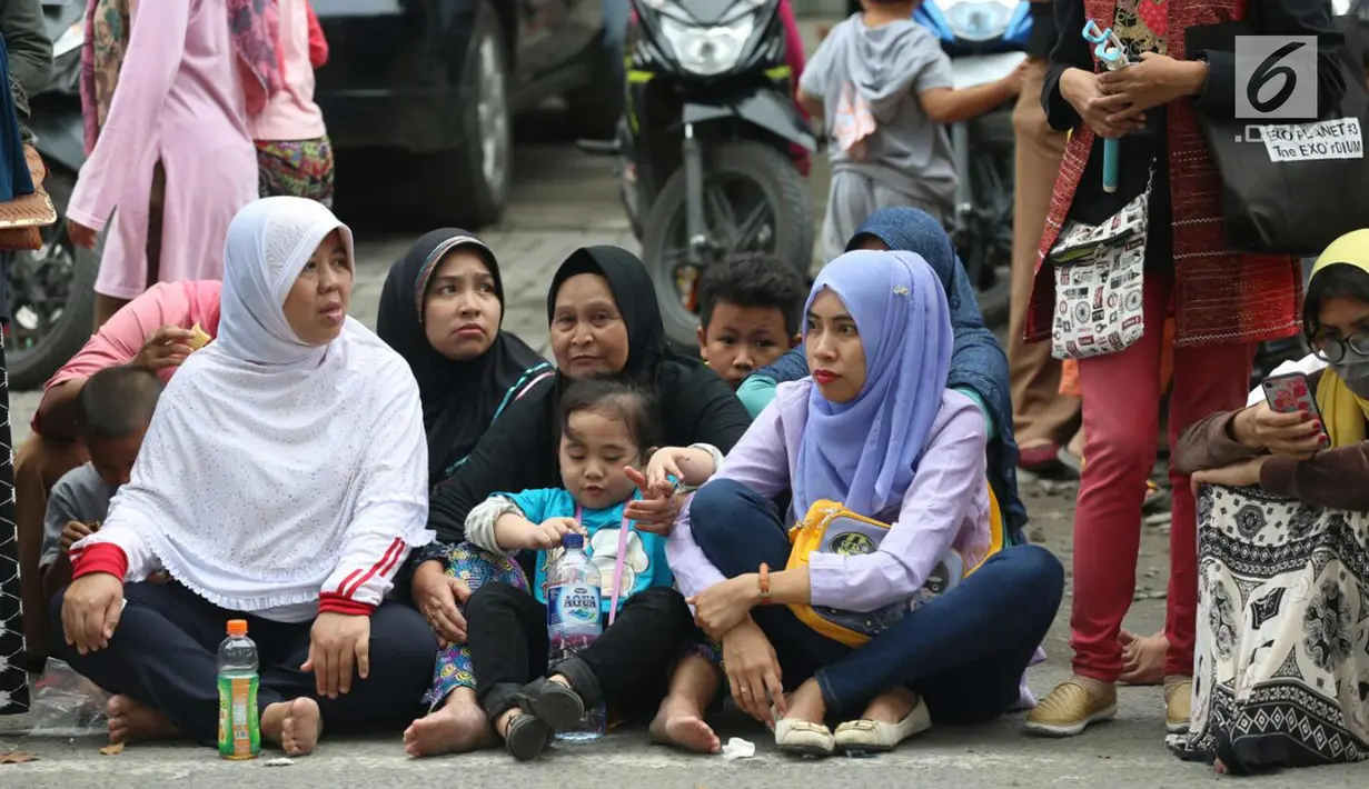 Warga duduk di jalan jelang kirab atau arak-arakan acara resepsi Kahiyang Ayu Siregar-Bobby Nasution di Kota Medan, Sumatera Utara Minggu (26/11). (Liputan6.com/Johan Tallo)