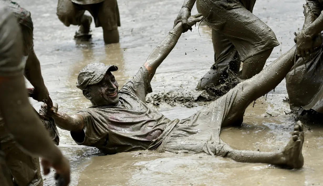 Para petani berlumur lumpur saat bermain pada Hari Padi Nasional di sawah Desa Tokha, Kathmandu, Nepal, Senin (29/6/2020). Para petani di Nepal merayakan Hari Padi Nasional sebagai musim tanam padi tahunan dimulai. (PRAKASH MATHEMA/AFP)