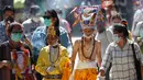 Anggota komunitas Newar mengenakan kostum dan masker saat berpartisipasi dalam prosesi 'Gai Jatra', atau festival sapi, di Kathmandu, Nepal, Selasa (4/8/2020). Sapi dianggap sebagai hewan suci bagi pemeluk Hindu yang membantu jiwa-jiwa yang telah pergi mencapai surga. (AP Photo/Niranjan Shrestha)