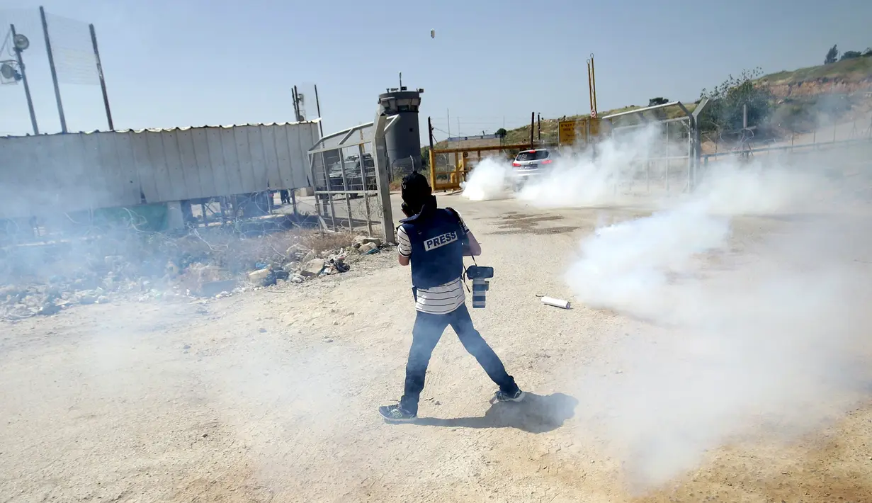 Seorang wartawan saat menghindari gas air mata yang ditembakkan pasukan Israel saat meliput aksi protes yang menyerukan pembebasan wartawan Palestina, Omar Nazzal di dekat Penjara Ofer Israel di Ramallah, Israel (26/4).(REUTERS / Mohamad Torokman)
