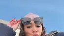 Naysila tampil mengenakan balutan outfit serba putih dengan sentuhan pink pada syal dan headwrap-nya, serta kacamata hitam yang menambah kesan stylish. [@naymirdad].