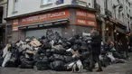 Seorang pria berjalan melewati tumpukan sampah di Paris, Senin (13/3/2023). RUU kontroversial yang akan menaikkan usia pensiun di Prancis dari 62 menjadi 64 tahun mendapat dorongan dengan adopsi tindakan Senat di tengah pemogokan, protes, dan sampah yang tidak diambil menumpuk semakin tinggi dari hari ke hari. (AP Photo/Lewis Joly)