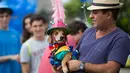 Seekor anjing dihias dan mengenakan kostum digendong pemiliknya saat mengikuti karnaval anjing "Blocao" di pantai Copacabana di Rio de Janeiro, Brasil (4/2). Karnaval Blocao ini bagian dari karnaval tahunan di Ibu Kota Brasil. (AP Photo/Silvia Izquierdo)