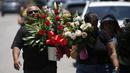 Orang-orang membawa bunga saat berjalan menuju tugu peringatan di luar Robb Elementary School untuk menghormati para korban yang tewas dalam penembakan di sekolah pekan ini, Uvalde, Texas, Amerika Serikat, 28 Mei 2022. (AP Photo/Dario Lopez-Mills)