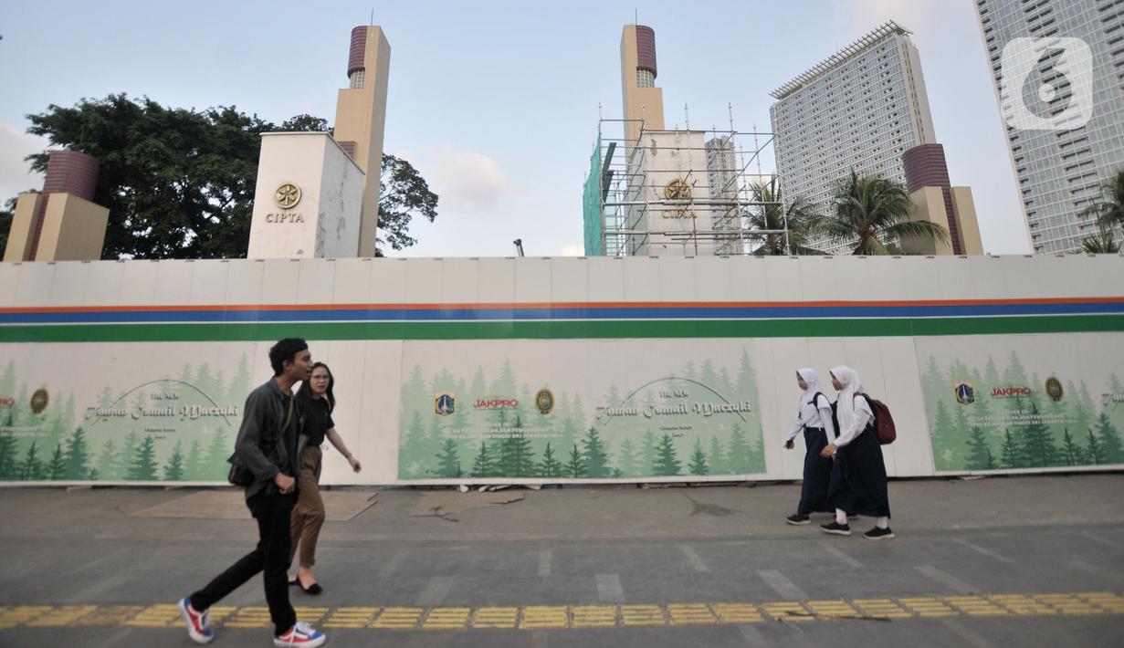 Pejalan kaki melintas di depan proyek revitalisasi Taman Ismail Marzuki (TIM), Jakarta, Selasa (26/11/2019). Pembangunan hotel berbintang di proyek revitalisasi TIM menuai penolakan dari seniman karena dinilai menjadi area komersial serta menggangu ruang berekspresi. (merdeka.com/Iqbal Nugroho)
