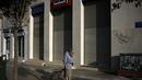 Seorang wanita melintas di depan sebuah bank yang berhenti beroperasi di Athena, Yunani, (29/6/2015). Seperti dikutip BBC, penarikan uang pun dibatasi hanya 60 euro per hari. (REUTERS/Alkis Konstantinidis)