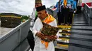 Para calon jemaah haji Indonesia turun dari pesawat Boeing 737 yang sudah tidak digunakan lagi selama sesi pelatihan keselamatan pra-keberangkatan di pusat embarkasi haji Banda Aceh pada Kamis 14 Mei 2026. (CHAIDEER MAHYUDDIN/AFP)