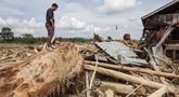 Seorang pria mencari sisa-sisa rumahnya yang terkubur di bawah tumpukan pohon tumbang yang disapu banjir bandang, di desa Lintang Bawah, Aceh Tamiang, Sumatera Utara, pada Kamis 11 Desember 2025. Banjir bandang dan longsor yang menerjang Aceh, Sumatera Utara, dan Sumatera Barat yang terjadi pada 25 November 2025 lalu mengakibatkan kerusakan parah pada sejumlah wilayah, salah satunya desa Lintang Baru di Aceh Tamiang. (Aditya Aji/AFP)