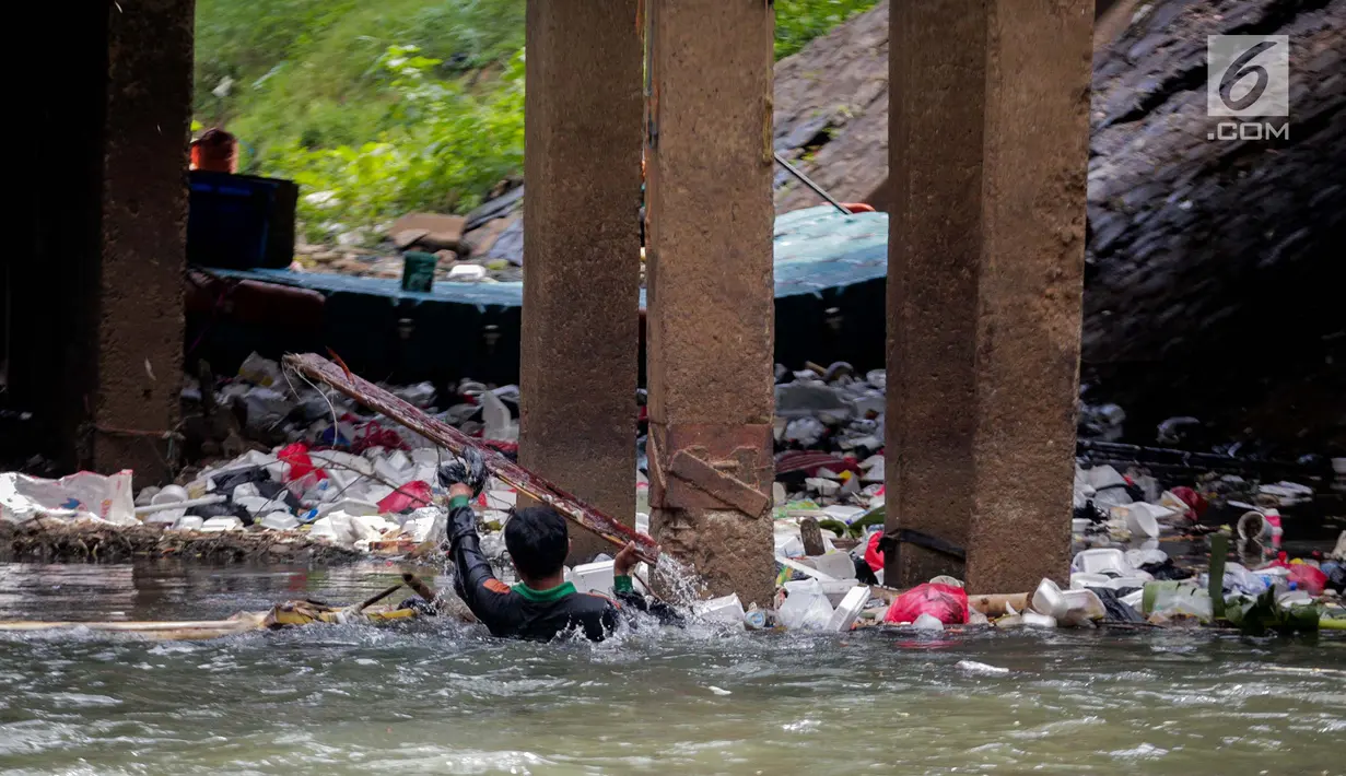 Aksi petugas PPSU bersihkan sampah yang tersangkut ditengah deras arus aliran anak kali Ciliwung, Jakarta, Senin (22/7/2019). Pembersihan sungai dari berbagai sampah tersebut dimaksudkan agar tidak ada penumpukan sampah dan sedimentasi saluran di sepanjang sungai. (Liputan6.com/Faizal Fanani)