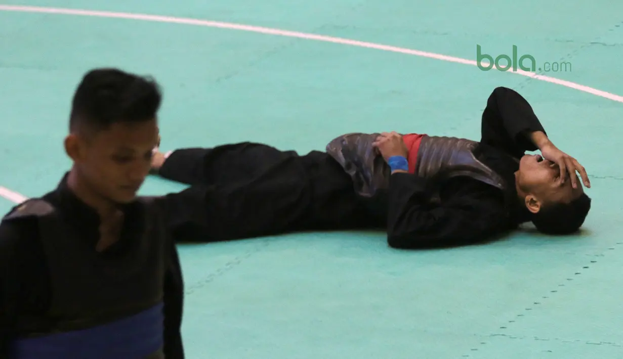 Arafa M. Yachser jatuh setelah wajahnya terkena pukulan pesilat Malaysia, Shukor M. Z. Hakim pada semifinal putra kelas 55 kg - 60 kg Test Event Pencak Silat 2018 di Padepokan Silat TMII, Jakarta, (12/2/2018). Arafa menang 5-0. (Bola.com/Nick Hanoatubun)