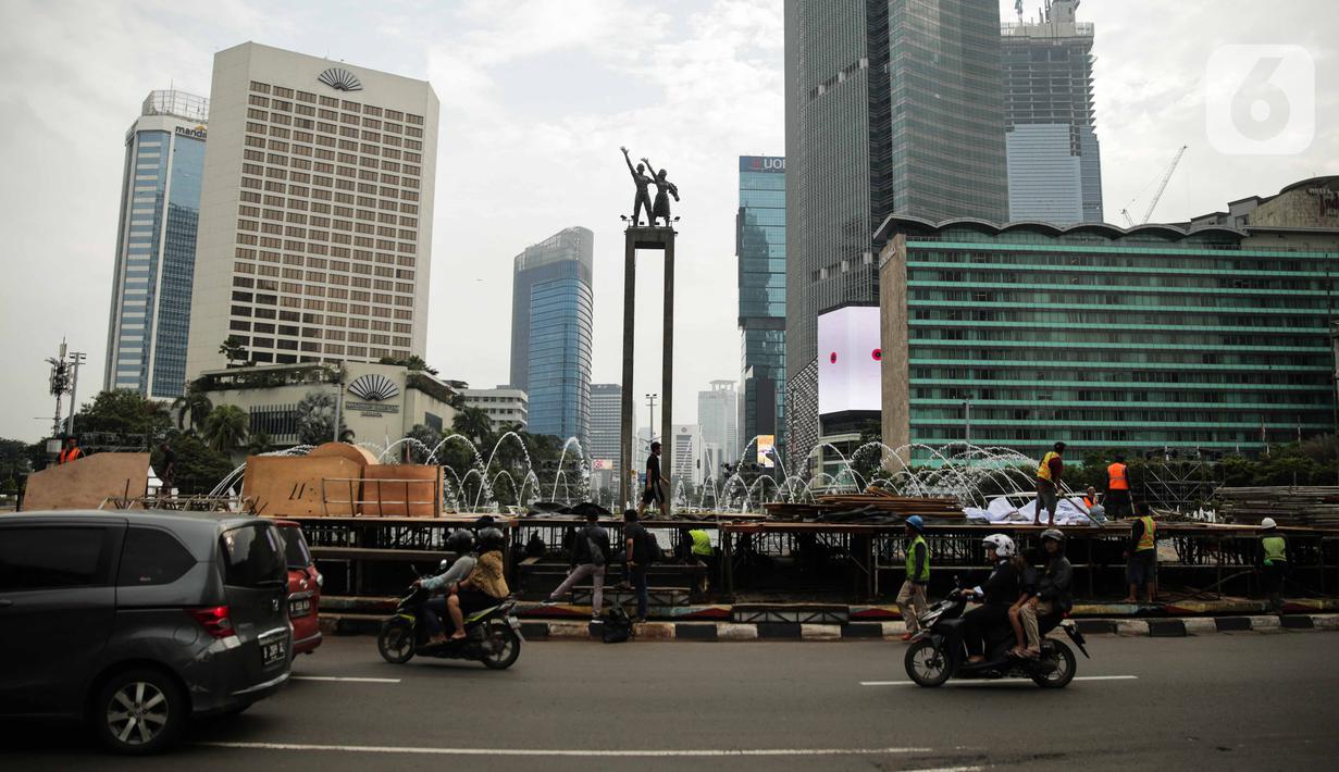 Kendaraan melintas dekat  pembuatan panggung untuk acara malam tahun baru di sekitar kawasan Bundaran HI, Jakarta, Rabu (25/12/2019). Merayakan pergantian tahun, Pemprov DKI Jakarta menggelar sejumlah acara di sejumlah titik sepanjang Jalan Sudirman-MH Thamrin. (Liputan6.com/Faizal Fanani)