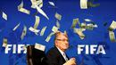 Ekspresi Presiden FIFA, Sepp Blatter, sesaat setelah di lempar segepok uang dollar oleh pelawak Inggris, Simon Brodkin, jelang konferensi pers di kantor FIFA di Zurich, Swiss. (20/7/2015). (REUTERS/Arnd Wiegmann)