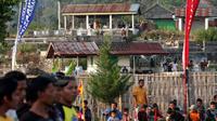 Warga dengan santainya menyaksikan sebuah pertandingan Piala Bupati Karanganyar di stadon mini Plumbon, Tawangmangu dari sebuah makam yang tak jauh dari lokasi pertandingan. (Bola.com/Romi Syahputra)