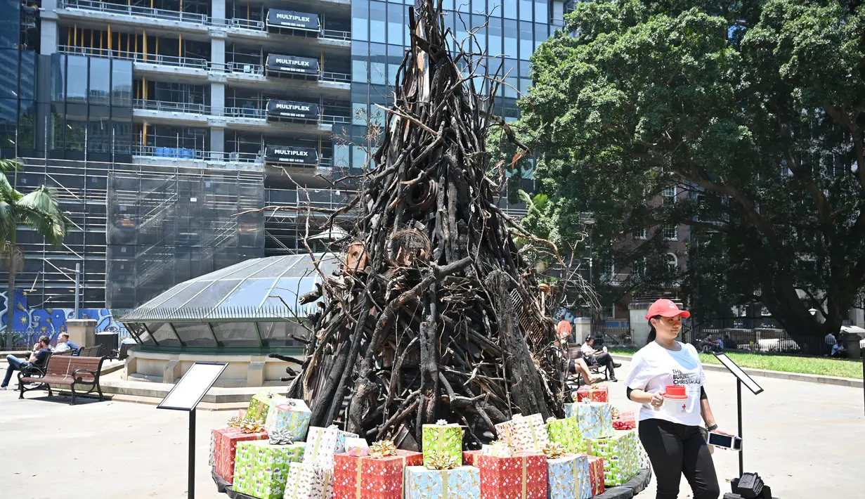 Seorang wanita berpose di depan instalasi yang dijuluki 'Pohon Natal yang Terbakar' di Sydney (18/12/2019). Warga Australia di pantai timur bersiap menghadapi "ancaman baru" ketika gelombang panas disertai dengan angin yang bergolak menurunkan lebih dari 100 kebakaran hutan di kawasan itu. (AFP/Pete