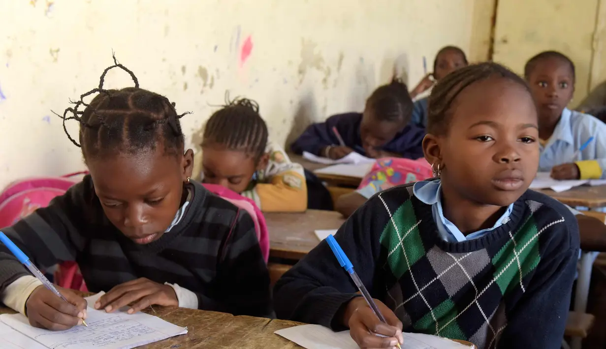 Dua murid saat menghadiri kelas di sekolah dasar di Pikine, di pinggiran Dakar, (30/1). Beberapa kepala negara, termasuk presiden Prancis dan Presiden Senegal mensponsori pertemuan tersebut. (AFP Photo/Seyllou)