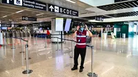 Petugas mengenakan termoscanner portabel "Smart-Helmet" untuk memeriksa suhu penumpang dan sesama staf di terminal keberangkatan bandara Fiumicino Roma, Italia pada 5 Mei 2020. Hal ini dilakukan guna menyaring orang yang memiliki gejala infeksi virus corona. (ANDREAS SOLARO/AFP)