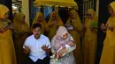 Seorang ibu mengendong bayinya saat ritual 'peutron tanoh aneuk' (turun tanah anak) di Banda Aceh, Aceh, Senin (15/7/2019). Ritual turun tanah anak telah menjadi tradisi sakral bagi masyarakat Aceh yang dilaksanakan pada saat bayi berusia 44 hari. (CHAIDEER MAHYUDDIN / AFP)