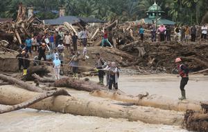 Warga yang menjadi korban banjir bandang di Batang Toru, Tapanuli Selatan, Sumatra Utara menggunakan kayu gelondongan untuk menyeberangi sungai, Selasa 2 Desember 2025. Warga Batang Toru, Tapanuli Selatan, terpaksa menggunakan jembatan darurat yang terbuat dari gelondongan kayu untuk menyeberangi sungai setelah jembatan utama rusak akibat terjangan banjir bandang baru-baru ini. (AP Photo/Binsar Bakkara)