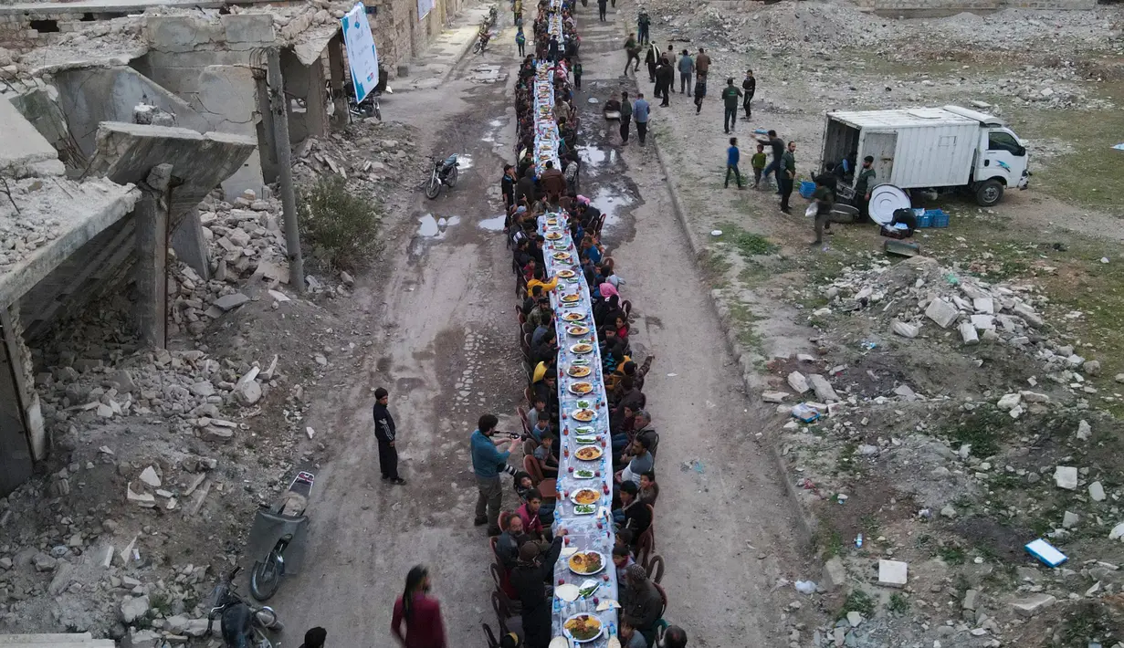 Pemandangan udara menunjukkan warga Suriah duduk di tengah-tengah bangunan yang rusak untuk berbuka puasa di Tadef, dekat kota perbatasan al-Bab, yang dikendalikan oleh pemberontak yang didukung Turki di Suriah di pedesaan timur provinsi Aleppo (18/4/2022). (AFP/Bakr Alkasem)