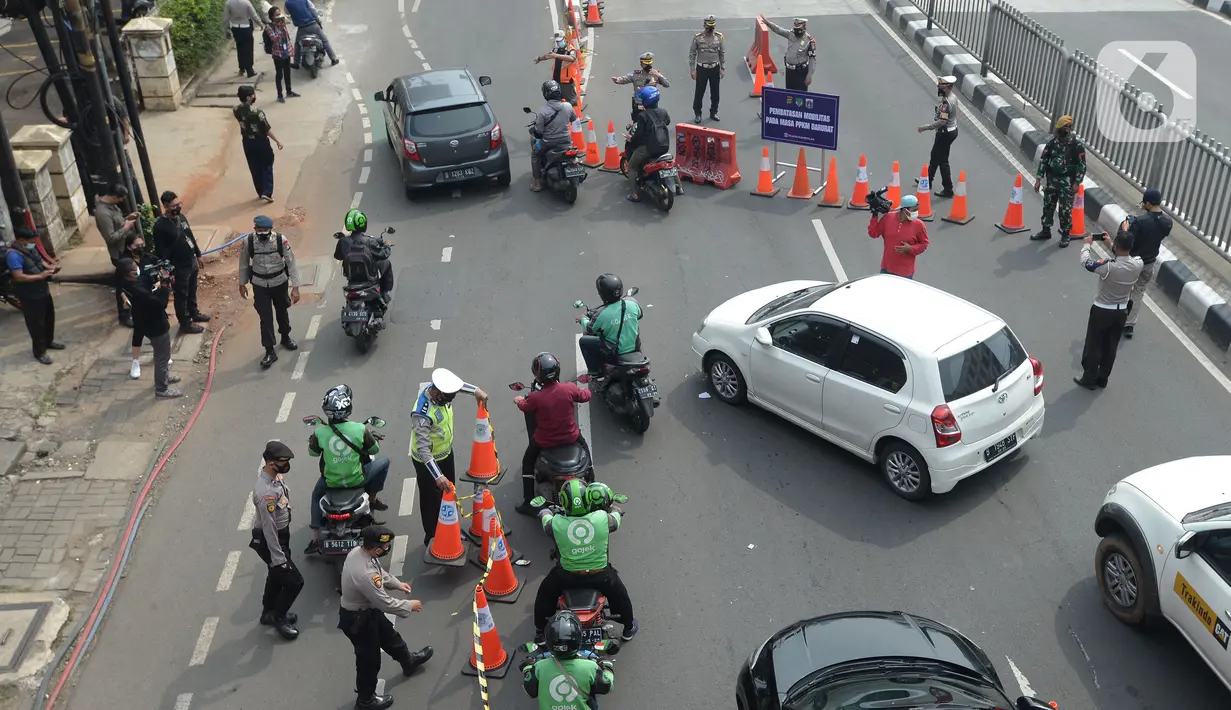 Petugas mengarahkan kendaraan saat penyekatan di ruas jalan Mampang Prapatan, Jakarta, Kamis (15/7/2021). Mampang menjadi salah satu jalan yang masuk dalam penyekatan baru pada Pemberlakuan Pembatasan Kegiatan Masyarakat (PPKM) darurat di Ibu Kota. (merdeka.com/Imam Buhori)