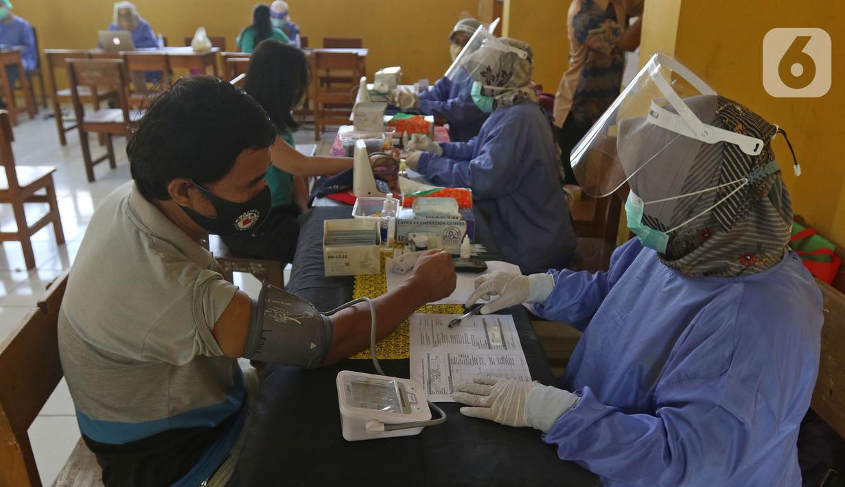 Petugas medis mengecek kesehatan warga sebelum divaksin di MTs As-Syafiiyah, Cilangkap, Jakarta, Kamis (3/6/2021).  Vaksinasi massal bagi warga RT 03/RW 03 Cilangkap, Cipayung, Jakarta Timur menggunakan vaksin produksi AstraZeneca. (Liputan6.com/Herman Zakharia)