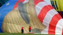 Dua orang wanita membantu mengempiskan balon dengan lukisan Konstitusi Amerika Serikat saat Festival Balon QuickChek New Jersey di Kota Readington, New Jersey (28/7). (AP Photo/Julio Cortez)