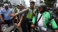 Petugas menenangkan pengadara Go-Jek yang terlibat kericuhan di Jakarta, Selasa (22/3). Ratusan Go-Jek mendatangi para sopir taksi karena tersebar isu pemukulan terhadap beberapa pengendara Go-Jek oleh sopir taksi.  (Liputan6.com/Immanuel Antonius)