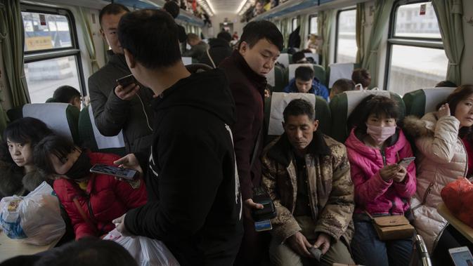 Penumpang menaiki kereta api menuju kota asal mereka di Beijing, Selasa (29/1). Jutaan orang China telah memulai migrasi manusia terbesar di dunia meninggalkan kota-kota besar menuju kampung halaman untuk merayakan Tahun Baru Imlek. (Nicolas ASFOURI/AFP)