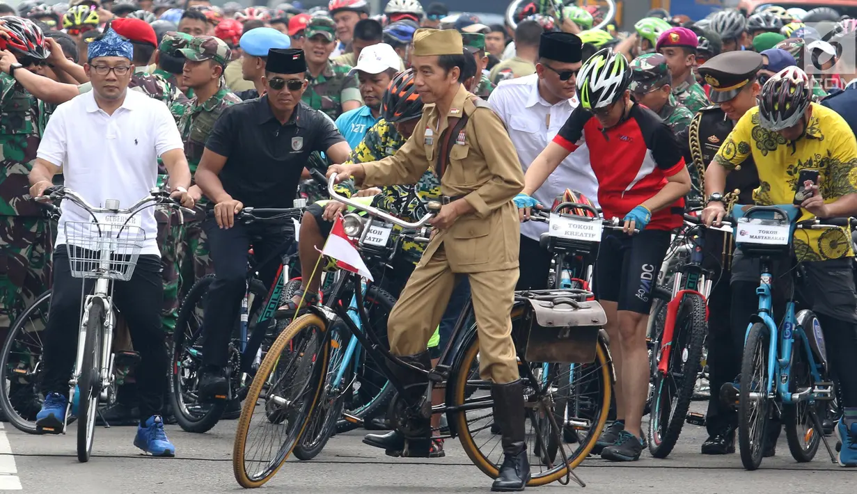 Presiden Joko Widodo atau Jokowi (tengah) didampingi Gubernur Jawa Barat Ridwan Kamil (kiri) saat mengikuti Bandung Lautan Sepeda, Sabtu (10/11). Jokowi berpakaian khas Sutomo atau Bung Tomo dalam kegiatan tersebut. (Liputan6.com/Angga Yuniar)
