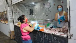 Pedagang membersihkan sekat tirai pelindung plastik pada kios jualan di pasar La Asuncion di Villa Nueva, Guatemala City pada 20 Juli 2020. Kios di pasar itu menggunakan tirai pelindung plastik untuk menjaga jarak fisik guna mengurangi resiko penyebaran virus Corona. (Johan ORDONEZ/AFP)