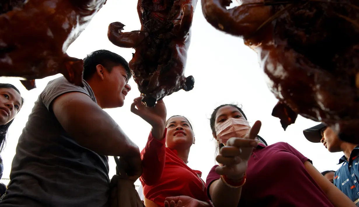 Pedagang babi panggang melayani pembeli di pasar di Phnom Penh, Kamboja (4/2). Menyambut Tahun Baru Imlek, warga Kamboja mempersiapkan daging babi panggang untuk sajian makan. (AFP Photo/Tang Chhin Sothy)