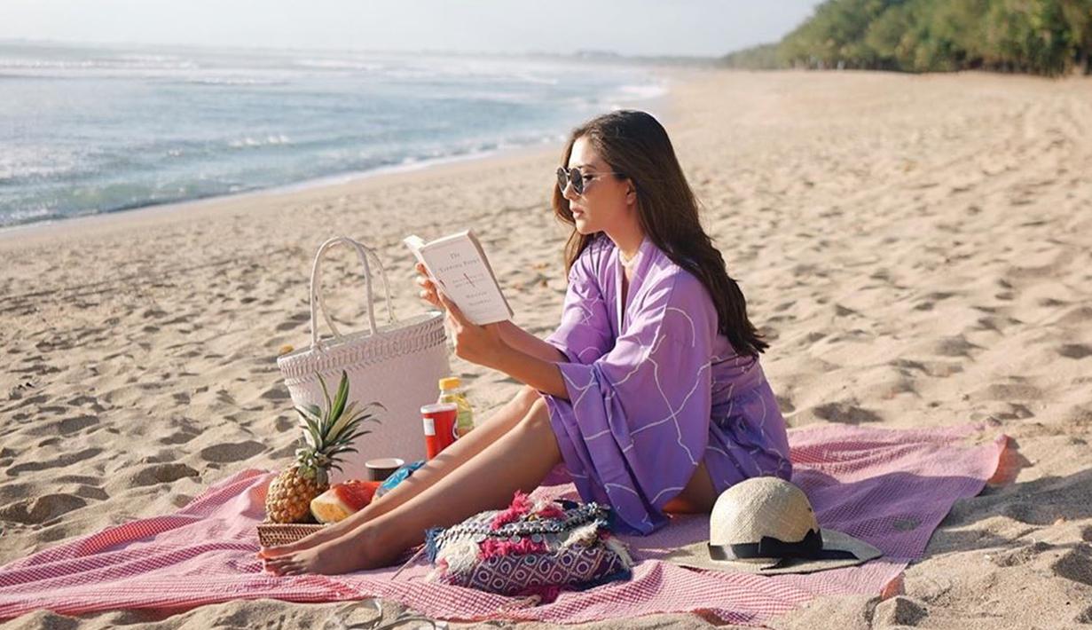 Mengikuti tren masa kini, Jessica Mila pun menggelar kain untuk piknik di pantai. Di momen pikniknya kali ini, ia nampak mengenakan jumpsuit warna ungu lilac dan mengenakan riasan natural. (Liputan6.com/IG/jscmila)