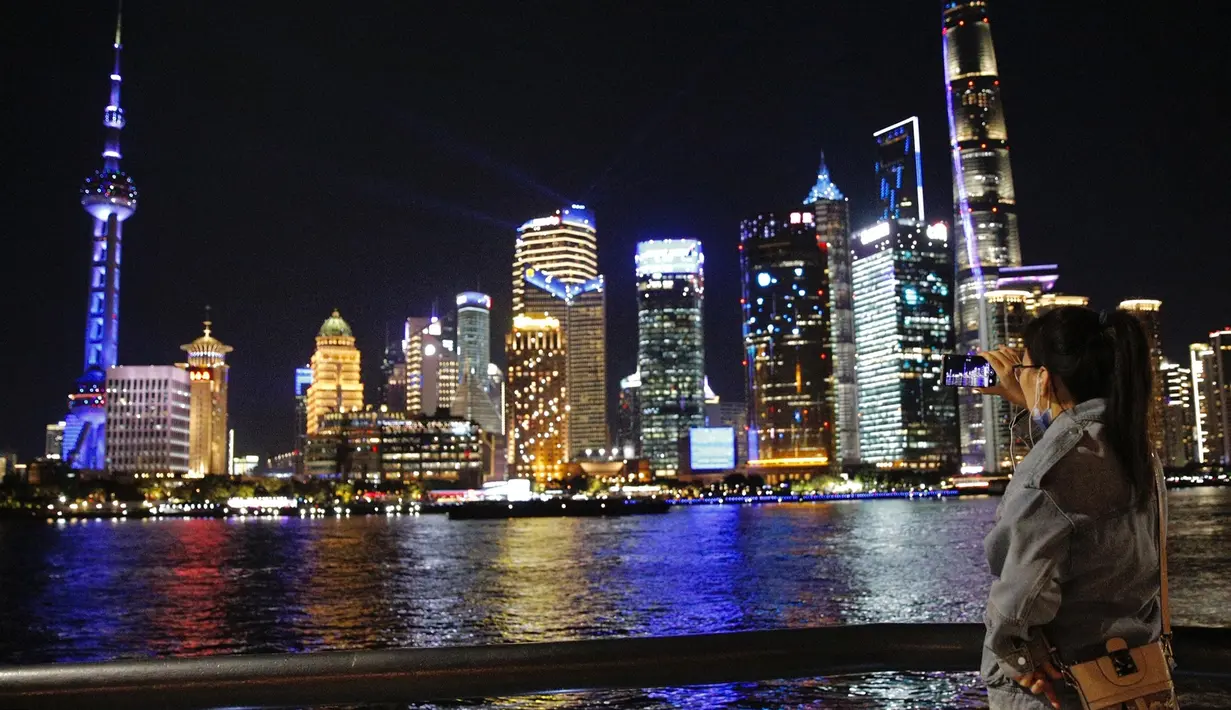 Seorang wisatawan merekam pertunjukan cahaya melalui ponsel di The Bund, Shanghai, China timur (4/11/2020). Sebuah pertunjukan cahaya bertema gelaran Pameran Impor Internasional China (China International Import Expo/CIIE) digelar di Lujiazui pada Rabu (4/11). (Xinhua/Zhang Haofu)