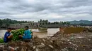 Pihak terkait akan terus mengerahkan kemampuan untuk melakukan upaya percepatan pemulihan infrastruktur dan konektivitas wilayah terdampak bencana. Tampak dalam foto, anak-anak duduk di dekat jembatan yang rusak akibat banjir di Juli, provinsi Aceh, pada Minggu 14 Desember 2025. (CHAIDEER MAHYUDDIN/AFP)