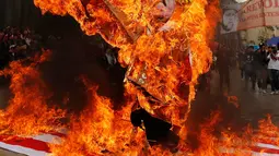 Para pengunjuk rasa membakar patung karakter Presiden AS Donald Trump saat melakukan aksi protes pada peringatan Hari Buruh di Bogota, Kolombia (1/5). Mereka melakukan aksi dengan membakar patung Donald Trump. (AP/Fernando Vergara)