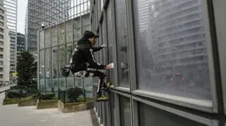 Pendaki Alain Robert atau French Spiderman mulai memanjat Menara Total di kawasan bisnis La Defense, Paris, Prancis, Senin (13/1/2020). Alain memanjat gedung tersebut tanpa menggunakan tali pengaman. (Thomas SAMSON/AFP)