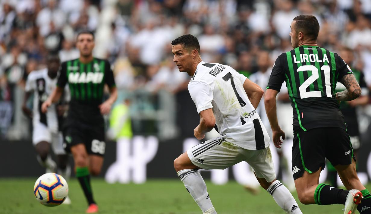 Striker Juventus, Cristiano Ronaldo, menghindari kejaran pemain Sassuolo pada laga Serie A di Stadion Juventus, Turin, Minggu (16/9/2018). CR 7 cetak dua gol, Juve menang 2-0 atas Sassuolo. (AFP/Miguel Medina)