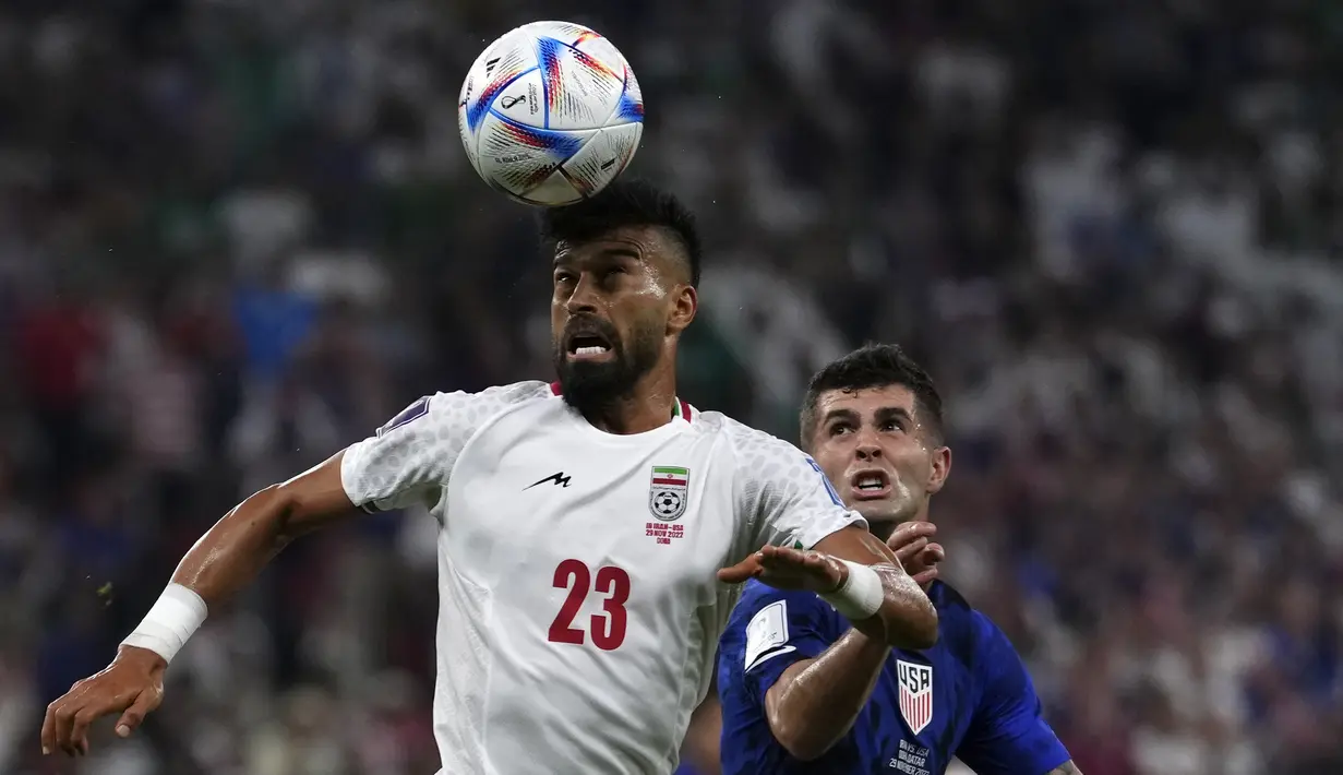 Gelandang Amerika Serikat Christian Pulisic menantang bek Iran Ramin Rezaeian pada laga pamungkas Grup B Piala Dunia 2022 di Stadion Al Thumama, Rabu (30/11/2022) dini hari WIB. Iran harus angkat koper lebih cepat setelah hanya meraih tiga poin dari tiga laga. (AP Photo/Manu Fernandez)
