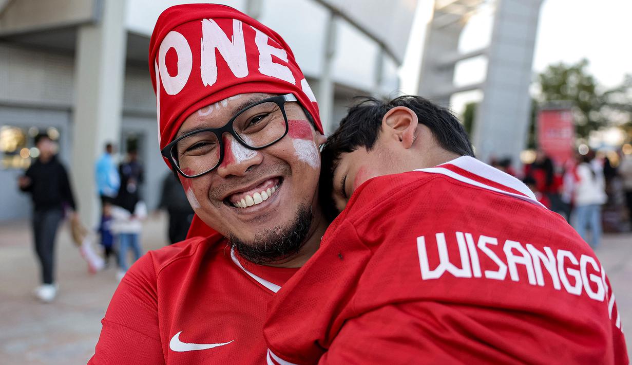 Seorang suporter Indonesia menggendong sang anak untuk menyaksikan laga kedua Grup D Piala Asia 2023 antara Timnas Indonesia menghadapi Vietnam di Abdullah Bin Khalifa Stadium, Doha, Qatar, Jumat (19/1/2024). (AFP/Karim Jaafar)