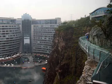 Pengunjung berjalan dekat Hotel Intercontinental Shanghai Wonderland di distrik Songjiang, Shanghai, 15 November 2018. China membuat sebuah hotel mewah pertama di dunia pada sebuah lokasi bekas lubang pertambangan yang amat dalam. (AP Photo)