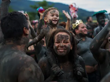Seorang anak bersama ibunya mengikuti festival tradisional "Bloco da Lama" atau "Mud Street" di Paraty, Brasil (25/2). Dalam bahasa Inggris, Bloco da Lama disebut dengan 'mud street party' atau pesta lumpur. (AP Photo / Mauro Pimentel)