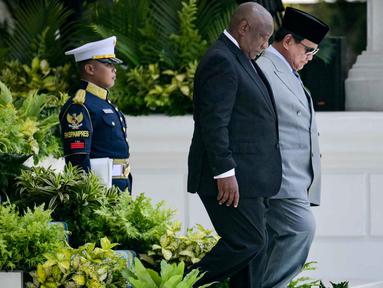 Presiden Republik Indonesia Prabowo Subianto (kanan) berjalan bersama Presiden Afrika Selatan Cyril Ramaphosa untuk memeriksa pasukan kehormatan di Istana Kepresidenan, Jakarta pada Rabu 22 Oktober 2025. (Bay ISMOYO/AFP)