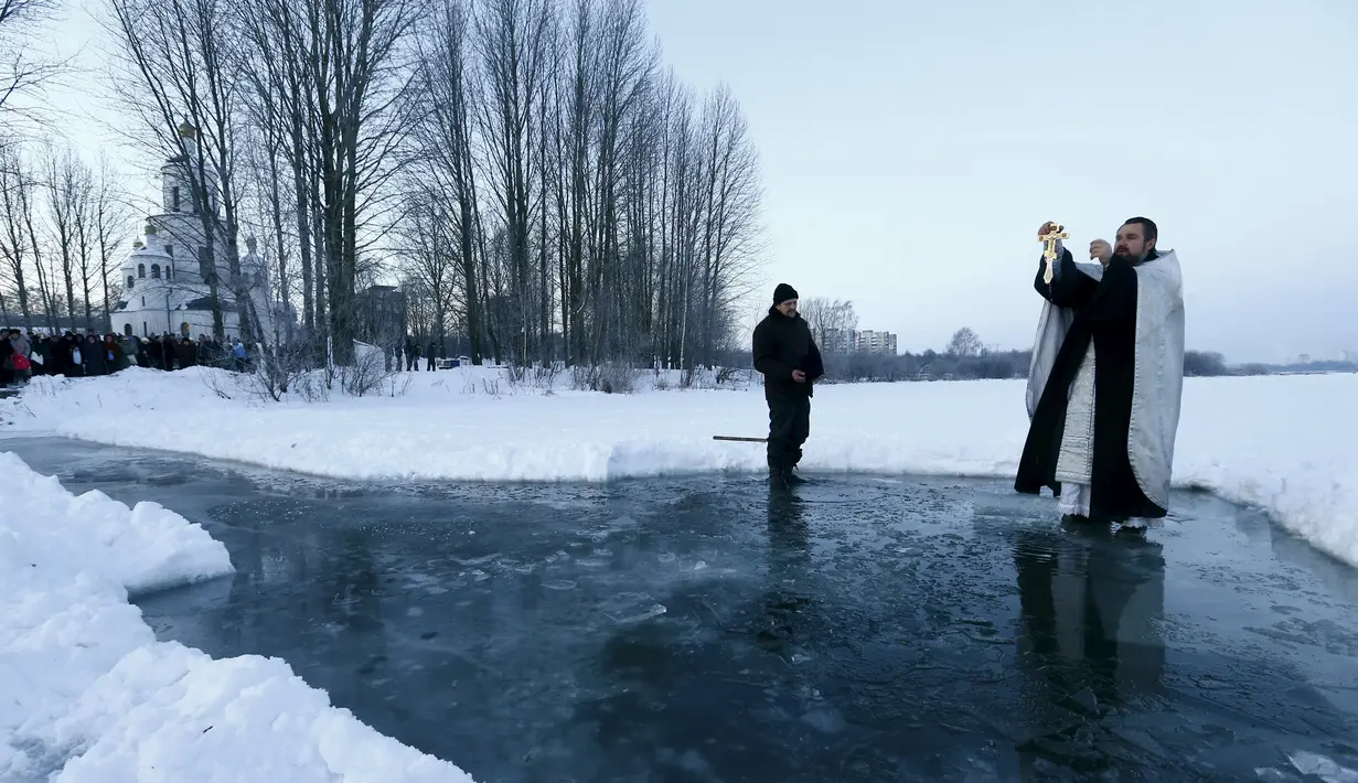 Pendeta Ortodoks memimpin di atas danau es dalam prosesi perayaan Epifani Ortodoks di Minsk, Belarusia (19/1/2016). Perayaan ini diwajibkan mandi dalam kolam berisi air suci, dalam kondisi cuaca apapun. (REUTERS/Vasily Fedosenko)