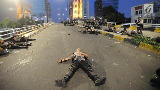 Anggota Dalmas BKO dari Polda Bali beristirahat usai mengamankan perusuh di atas fly over Slipi, Jakarta, Rabu (22/5/2019). Bentrokan panjang dengan para perusuh membuat anggota kepolisian yang berhadapan langsung kurang beristirahat.