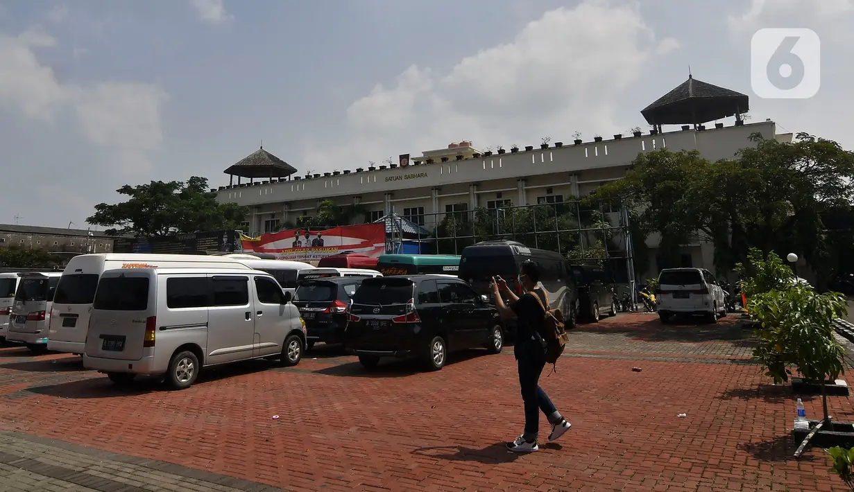 Seorang pewarta mengambil gambar mobil travel gelap yang disita di halaman Polres Metro Kabupaten Bekasi, Jawa Barat, Senin (10/5/2021). Satlantas Polres Metro Bekasi mengamankan 32 travel gelap yang masih beroperasi saat larangan mudik dari tanggal 6-17 Mei 2021. (Liputan6.com/Herman Zakharia)