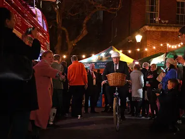 Perdana Menteri Inggris Boris Johnson mengendarai sepeda saat kunjungannya ke pasar Makanan dan Minuman Inggris yang didirikan di Downing Street, London, 30 November 2021. Sebanyak 12 bisnis dari seluruh Inggris memiliki kios untuk memamerkan produk mereka. (JUSTIN TALLIS/AFP/POOL)