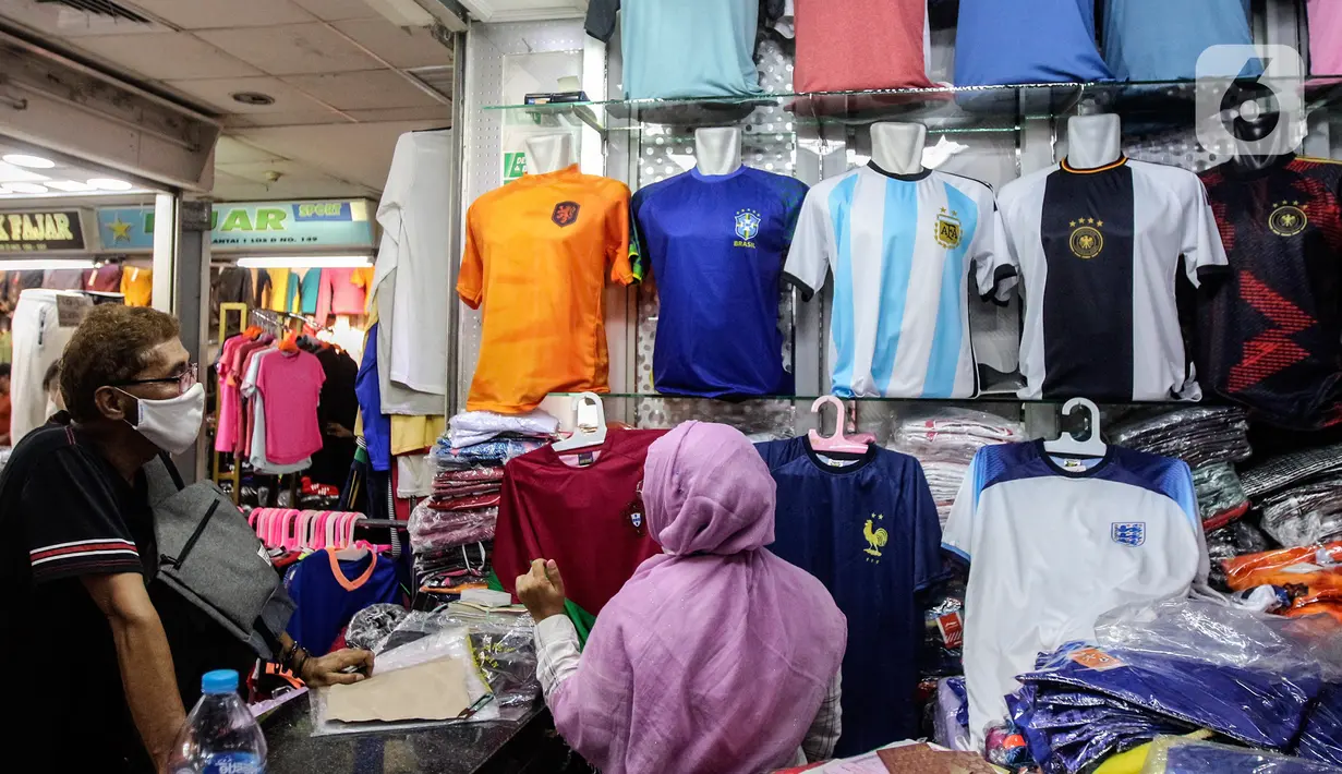 Pedagang melayani pembeli jersey timnas sepak bola peserta Piala Dunia Qatar 2022 di salah satu kios Blok B Pasar Tanah Abang, Jakarta, Kamis (24/11/2022). Menurut pedagang, permintaan jersey timnas meningkat dikarenakan Piala Dunia Qatar 2022 yang dimulai sejak 20 November 2022. (Liputan6.com/Johan Tallo)