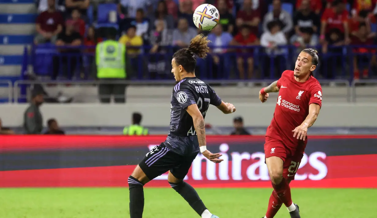 Bek Lyon, Malo Gusto (Kiri) dan bek Liverpool Yunani Kostas Tsimikas bersaing untuk mendapatkan bola selama pertandingan Dubai Super Cup 2022 di Al Maktoum Stadium, Uni Emirat Arab, Minggu (11/12/2022). Lyon menang atas Liverpool 3-1. (AFP/Karim Sahib)