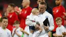 Striker Inggris, Wayne Rooney meggendong anaknya sebelum pertandingan persahabatan melawan Amerika Serikat (AS) di Stadion Wembley, Inggris (16/11). Wayne Rooney merupakan pencetak gol terbanyak di Timnas Inggris. (AFP Photo/Ian Kington)