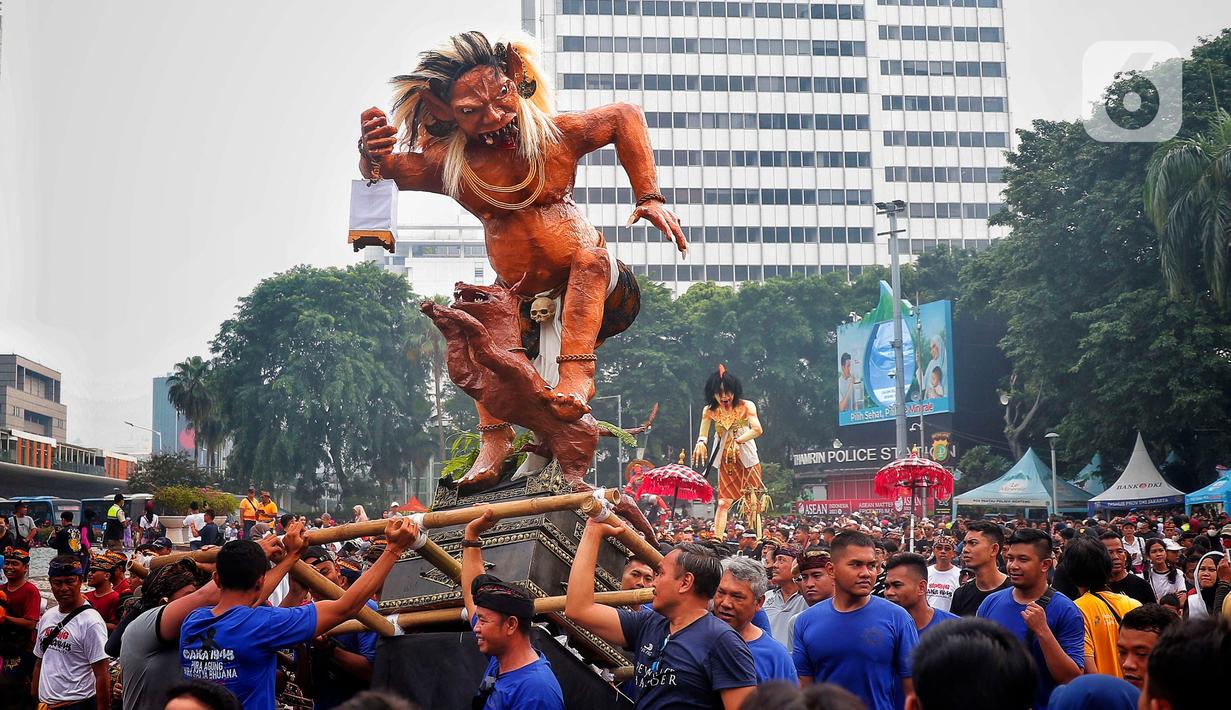 Umat Hindu mengarak ogoh-ogoh saat hari bebas berkendara di kawasan Bundaran HI, Jakarta, Minggu (12/3/2023). Ogoh-ogoh sendiri dalam kebudayaan Bali biasa menggambarkan kepribadian Bhuta Kala yang dalam ajaran Hindu Dharma merupakan kekuatan (Bhu) alam semesta dan waktu (Kala) yang tak terukur dan tak terbantahkan. (Liputan6.com/Angga Yuniar)